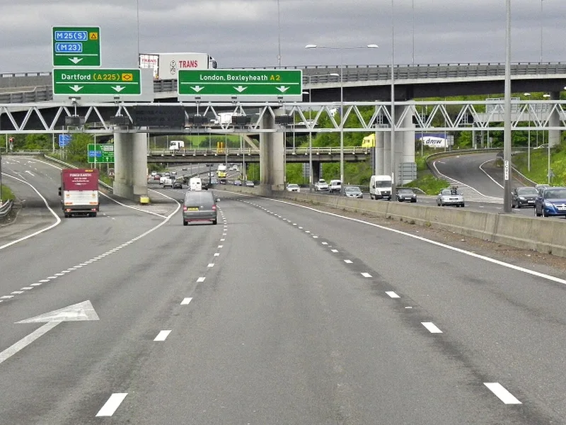 An overhead gantry at the A2 to M25 interchange in Kent showing a blue motorway direction sign for the M25 beside green primary-route signs for Dartford and London.