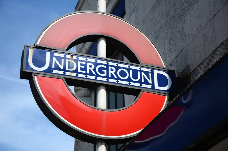 A red and blue London Underground roundel sign reading UNDERGROUND, mounted outside a station.